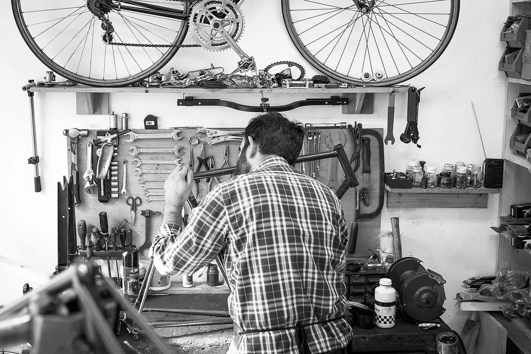 Mecánico trabajando en una bicicleta frente al panel de herramientas